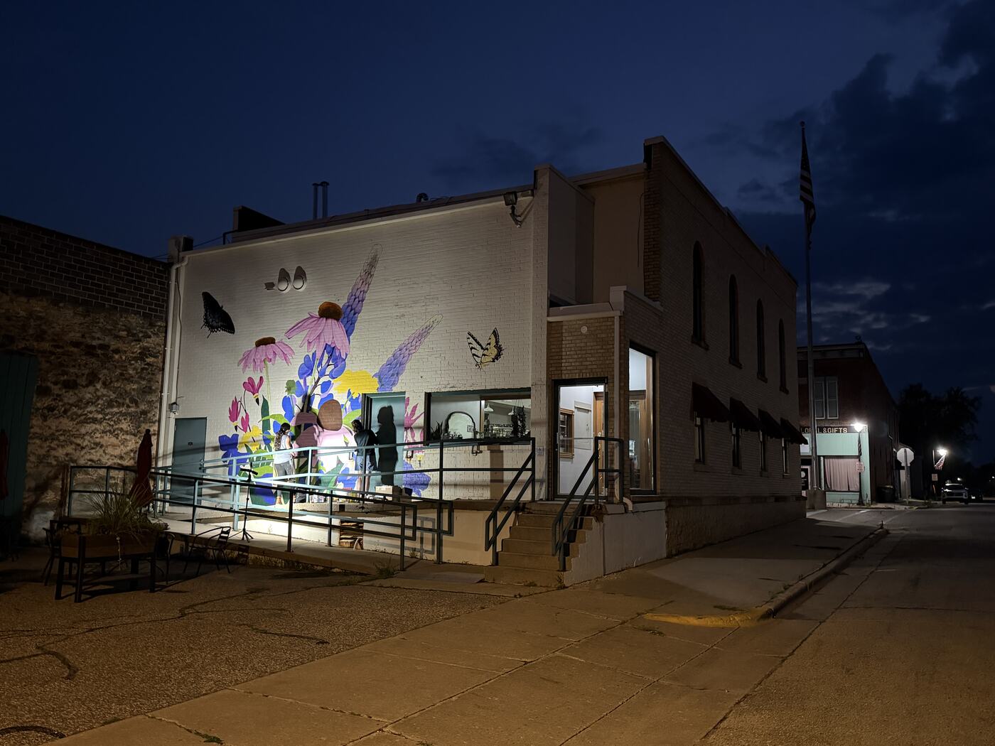 Muralist painting wildflowers and butterflies on the 1855 building at night under work lights